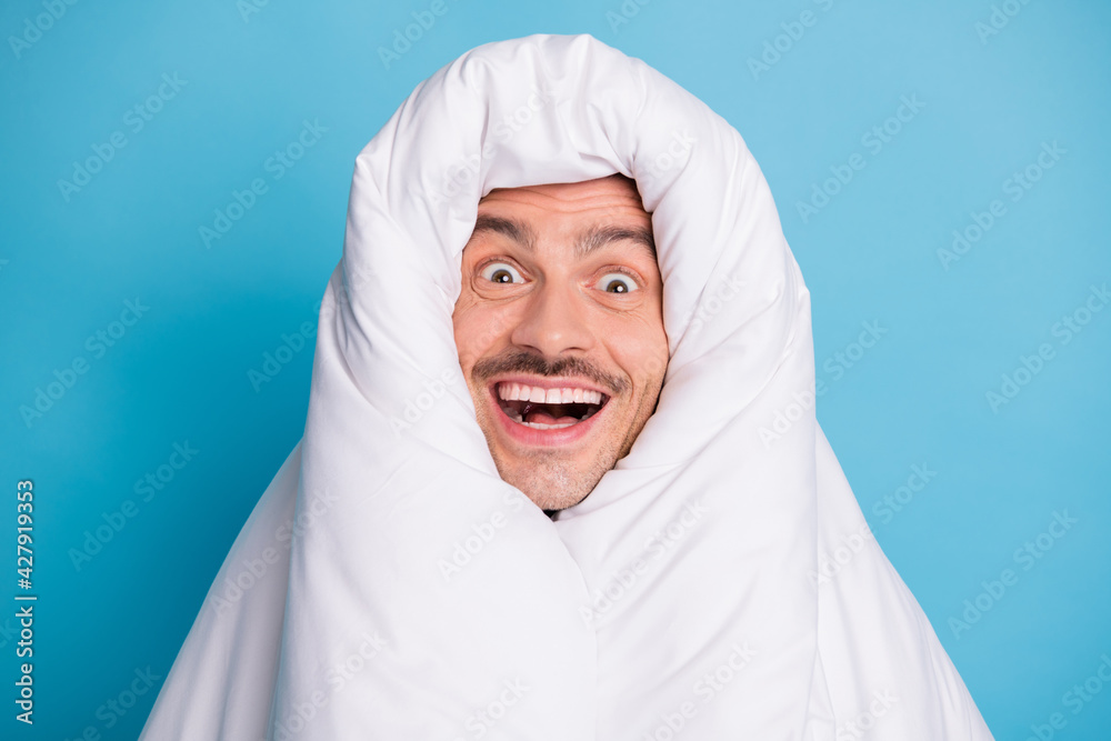 Photo portrait of excited screaming guy completely wrapped in duvet isolated on vivid blue colored background Photo portrait of excited screaming guy completely wrapped in duvet isolated on vivid blue colored background