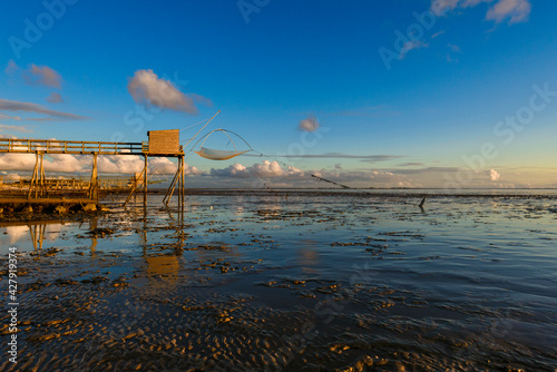 Un carrelet de peche se reflete à marée basse au coucher du soleil en bretagne