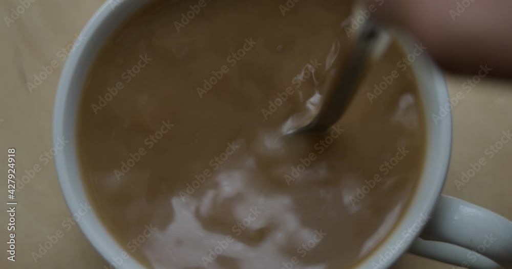 Slow Motion Man Stirs Sugar in Cup of Aromatic Coffee Closeup. Fresh Morning Over Black Tea With Milk Close Up. Selective Focus. Slow Motion Top View Person Hand Stirring Cup Hot Chocolate Or Coffee. Slow Motion Man Stirs Sugar in Cup of Aromatic Coffee Closeup. Fresh Morning Over Black Tea With Milk Close Up. Selective Focus. Slow Motion Top View Person Hand Stirring Cup Hot Chocolate Or Coffee.