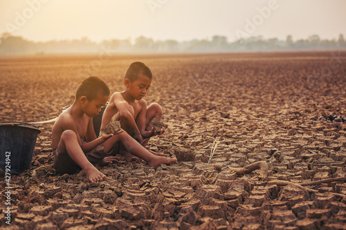 Climate change, Two Asian boys walking and searching for water on dry ground and sunset. Environment conservation and stop global warming concept