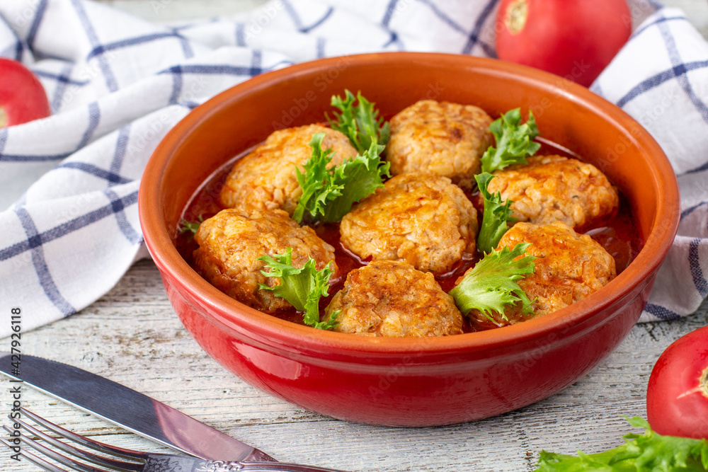Meatballs in tomato sauce in a bowl on wooden table.