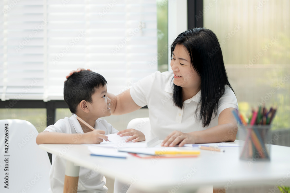 Mother and son doing homework at home, Mother is teaching son to draw pictures, Children homework. Young boy doing homework on the terrace at home. Happy mood. Back to school concept. Mother and son doing homework at home, Mother is teaching son to draw pictures, Children homework. Young boy doing homework on the terrace at home. Happy mood. Back to school concept.