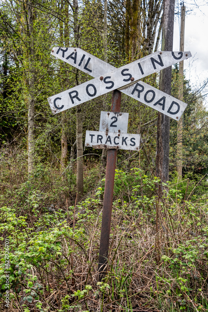 Old sign of railroad crossing on spring trees background