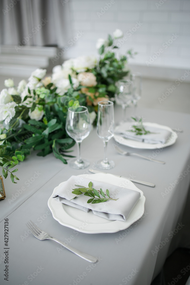 serving on the table of the newlyweds. White plate with glasses and utensils on the background of a blue tablecloth serving on the table of the newlyweds. White plate with glasses and utensils on the background of a blue tablecloth