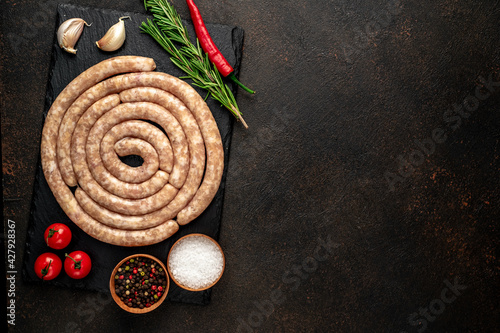 raw spiral chicken sausages with ingredients on stone background with copy space for your text