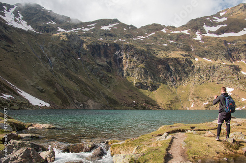 joven deportista tomando foto al lago entre montañas