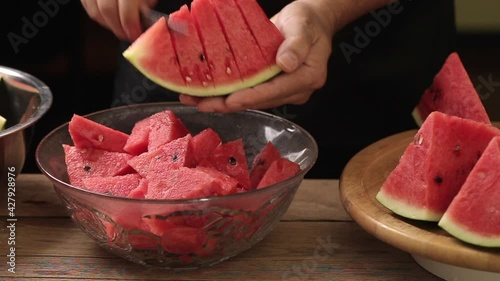 Man cutting watermelon into pieces on a wooden board