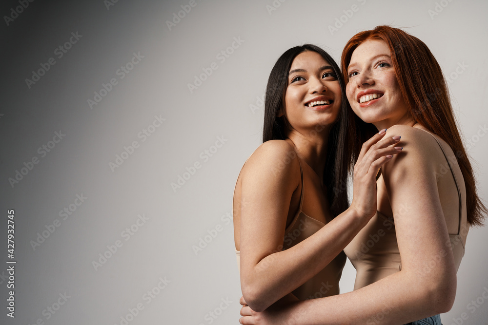 Multiracial two women hugging and laughing at camera Multiracial two women hugging and laughing at camera