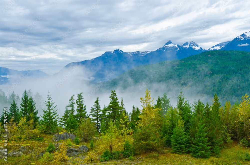 A beautiful view with cloudy sky with foggy mist around the mountains and trees in a beautiful and peaceful rural country scene.