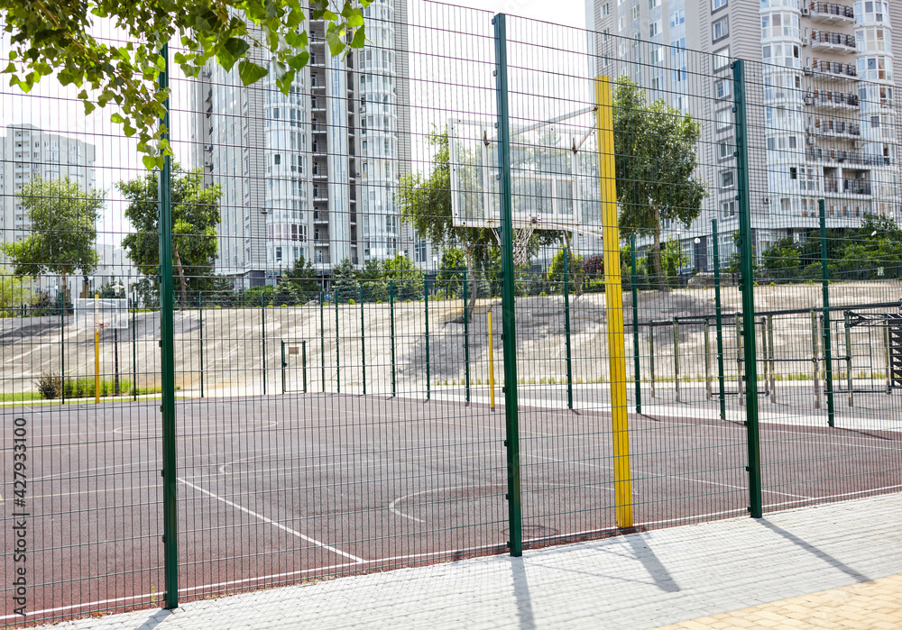 Basketball court from behind fence. Basketball hoop in the city park. Selective focus, blurred background Basketball court from behind fence. Basketball hoop in the city park. Selective focus, blurred background