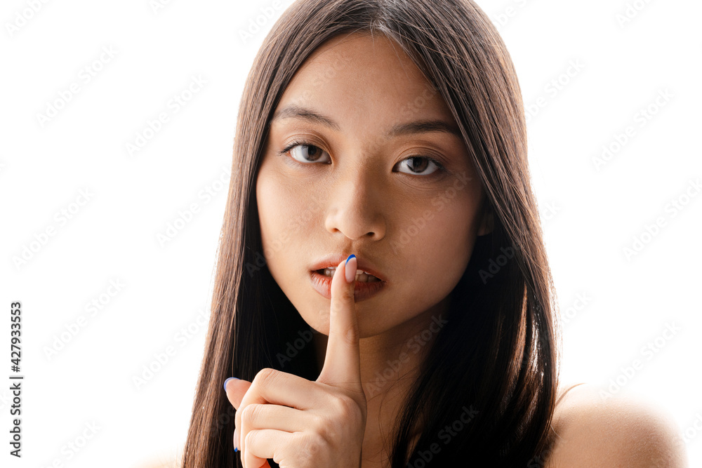 Young asian brunette woman looking and showing silence gesture at camera Young asian brunette woman looking and showing silence gesture at camera
