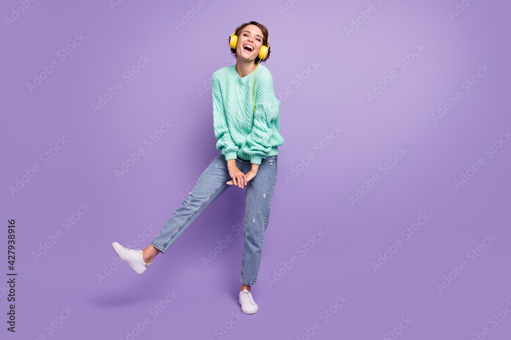Full length body size photo of dancing funky cheerful girl listening music in earphones isolated pastel purple color background Full length body size photo of dancing funky cheerful girl listening music in earphones isolated pastel purple color background