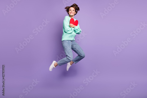 Full length body size view of attractive cheerful amorous girl jumping hugging heart card isolated over violet purple color background