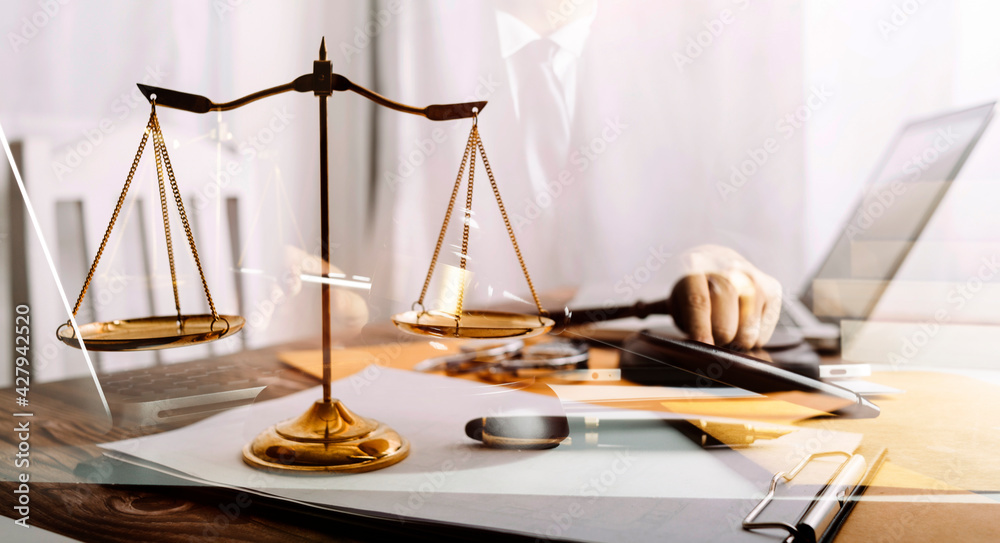 Business and lawyers discussing contract papers with brass scale on desk in office. Law, legal services, advice, justice and law concept picture with film grain effect Business and lawyers discussing contract papers with brass scale on desk in office. Law, legal services, advice, justice and law concept picture with film grain effect