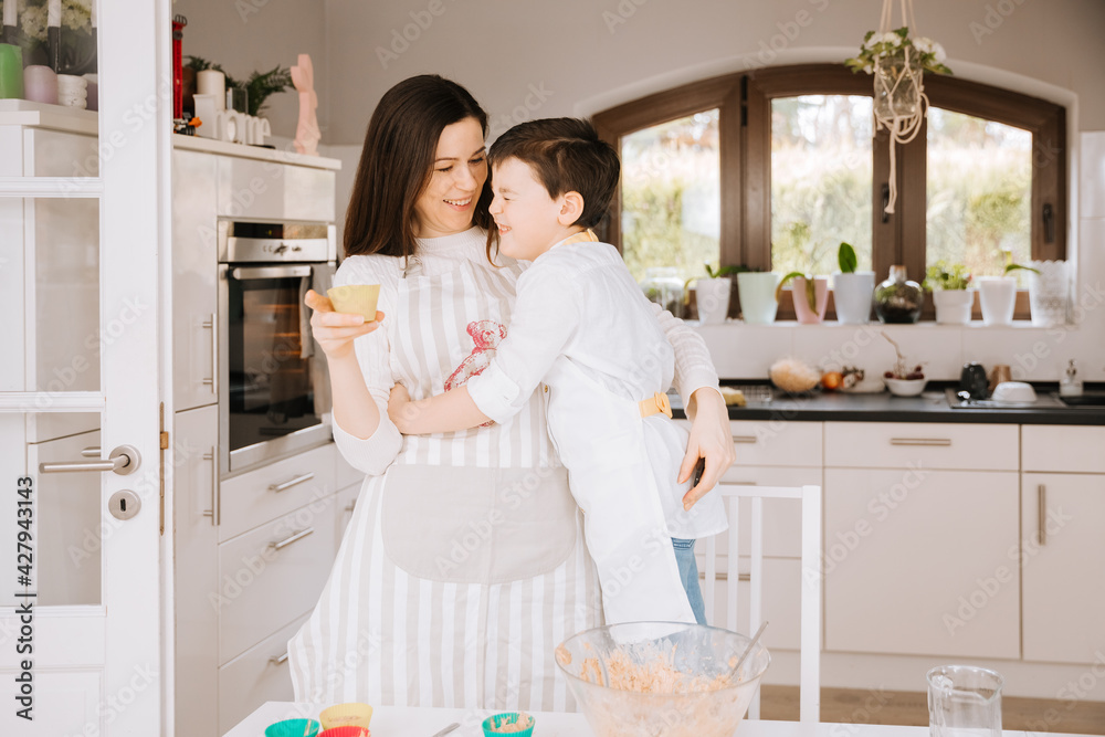 Little boy makes cupcakes with his mom. Child bakes cakes. Bake together during the pandemic. Cupcakes made by children. Mother and child in the kitchen	