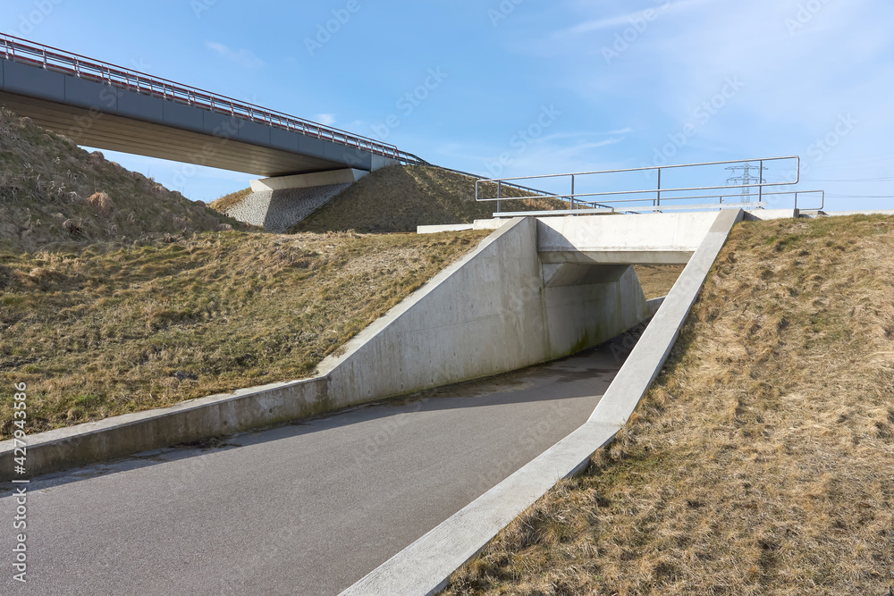 Empty overpass for cars and underpass for cyclists and pedestrians under a blue sky in early spring.