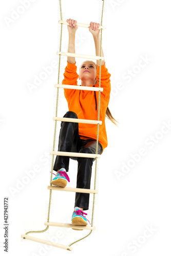 Sportive teen girl playing on rope ladder
