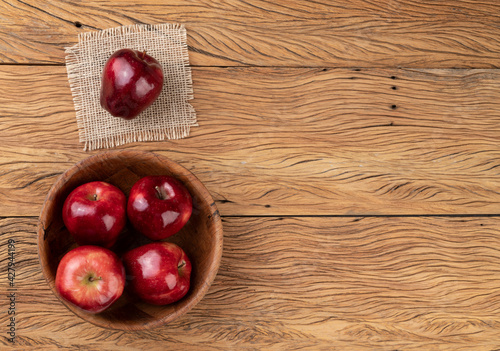 Red apples in a bowl over wooden table with copy space