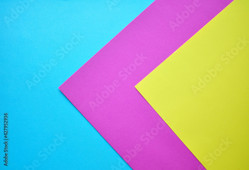 Multicolored paper, paper background. Colored paper in blue, pink and yellow.