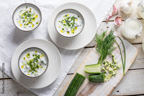Traditional summer cold soup of homemade yogurt, cucumbers and fresh herbs on a table