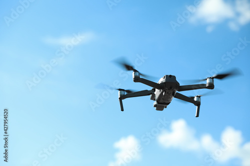 Modern drone with camera flying in sky on sunny day