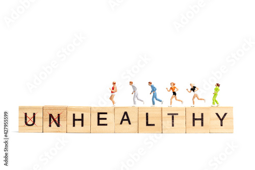 Miniature people running on wooden letter block on white background.Healthy concept