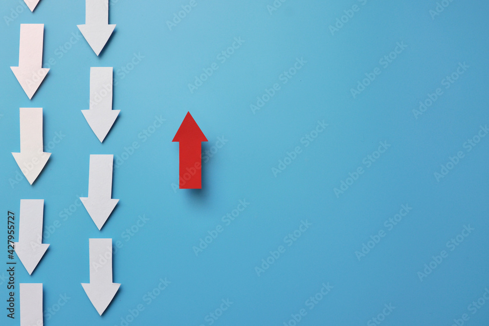 Many white arrows point down and one red arrow points up. A symbol of an innovative, different way in life and business Many white arrows point down and one red arrow points up. A symbol of an innovative, different way in life and business
