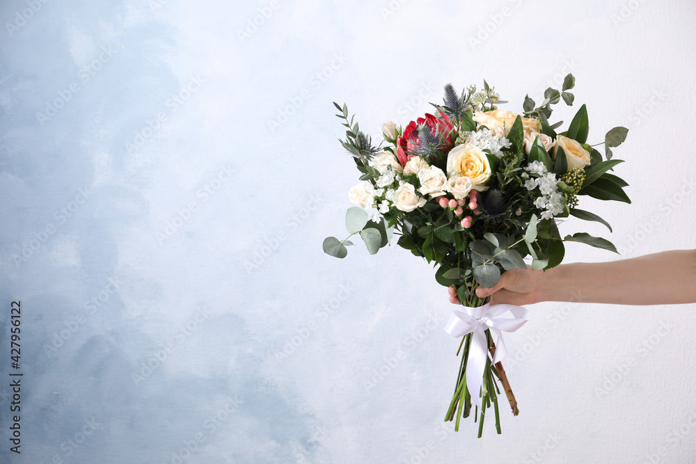 Woman with bouquet of beautiful roses on light blue background, closeup. Space for text