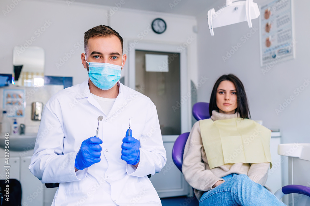 the patient is sitting in a dental chair. dentist in uniform hol