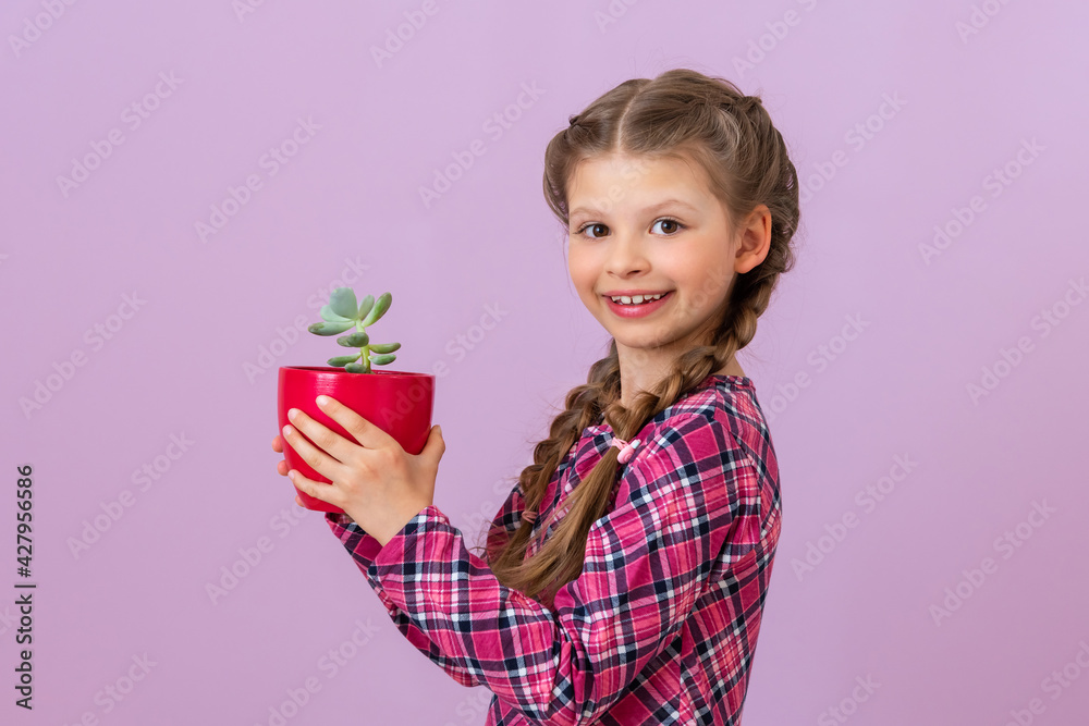 A little girl holds a red clay pot with a plant in it. A little girl holds a red clay pot with a plant in it.