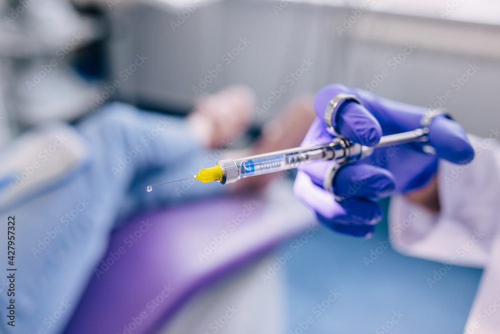 close-up of an anesthesia syringe in dentist hands. patient sitt close-up of an anesthesia syringe in dentist hands. patient sitt