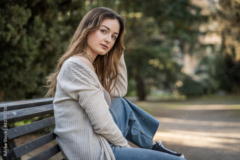 Pretty young woman sitting on a park bench Pretty young woman sitting on a park bench
