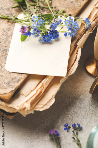 Fototapeta Naklejka Na Ścianę i Meble -  Beautiful Forget-me-not flowers and antique book on grey table, closeup