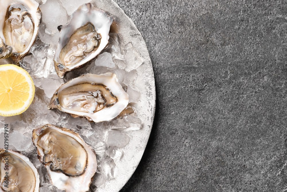 Delicious fresh oysters with lemon on grey table, top view Delicious fresh oysters with lemon on grey table, top view