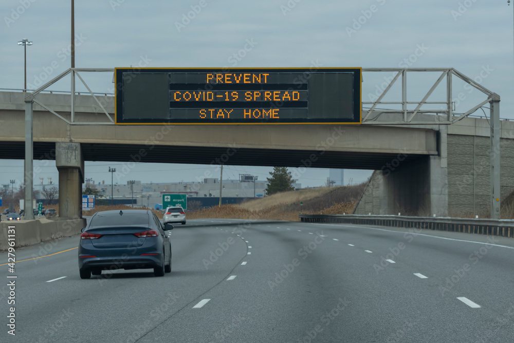 Sign prevent covid-19 spread, stay home on a scoreboard over highway during corona virus pandemic outbreak lockdown quarantine. Selective focus.