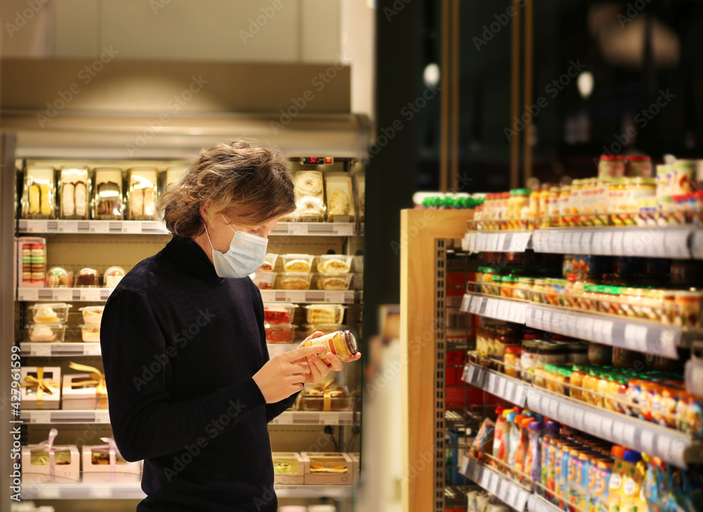 Supermarket shopping, face mask and gloves,Young man shopping in supermarket, reading product information