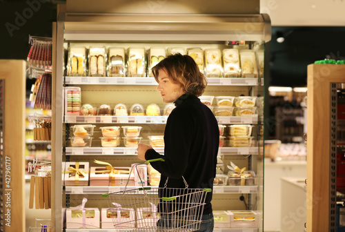 Young man shopping in supermarket, reading product information