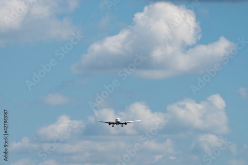The plane, painted in a white livery, comes in to land against the background of clouds in the sky.