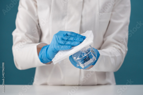 Handling and cleaning in blue gloves with a rag by a health worker of safety glasses after contact with a viral sick patient.