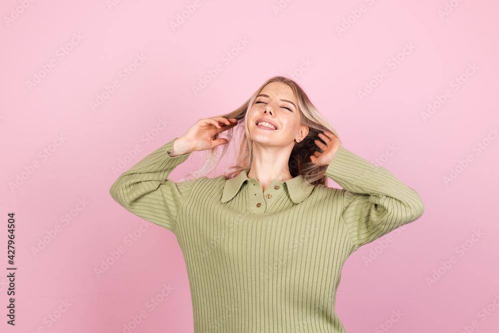 Pretty european woman in casual sweater on pink background cute smiling happy positive dancing moving