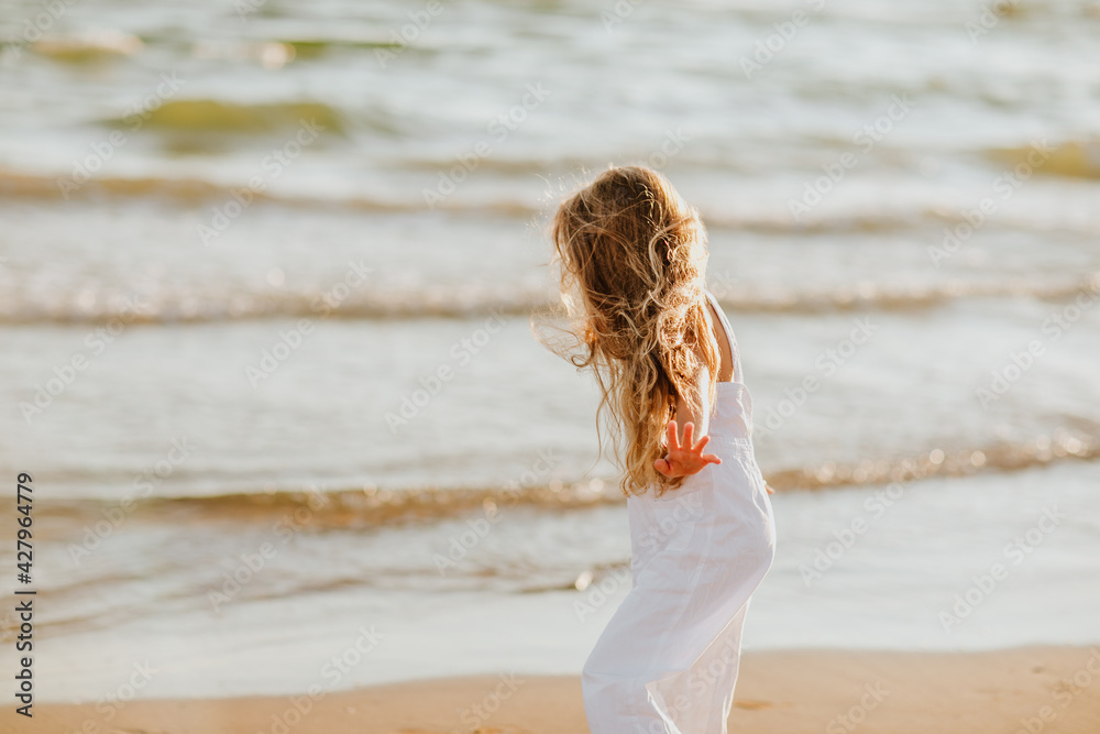 Girl in white summer overalls walking on a sea coast. Copy space. Girl in white summer overalls walking on a sea coast. Copy space.