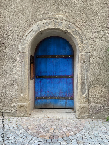 Altes Rundtor mit schwerer Holztür mit Eisenstreben blau angestrichen © Petra