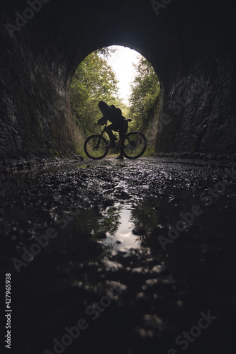 Wallpaper Mural Silhouette of a young cyclist on a bicycle at the exit of a tunnel. Via verde de Loredo in Asturias, old railway tracks converted into a path. Silhouette of a person on a bicycle, sporty and active. Torontodigital.ca