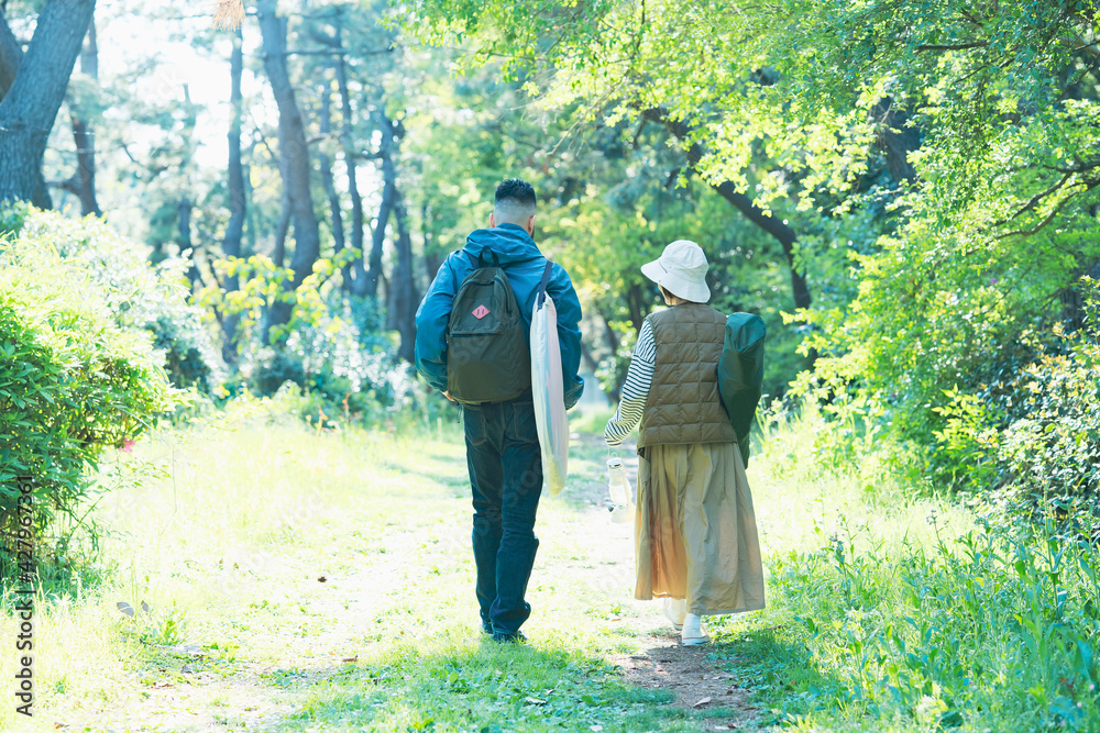 荷物を持ってキャンプ場に向かう男女 荷物を持ってキャンプ場に向かう男女
