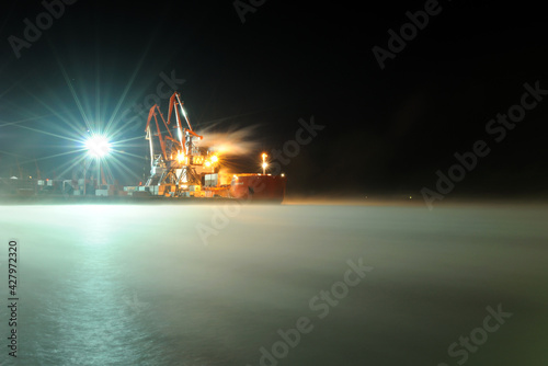 Murmansk, Russia - February 04, 2012: Icebreaker Zapolyarny on the water covered with a blanket of snow. An icebreaker stands in the port, lit by lanterns, in the early morning. Wallpaper. photo