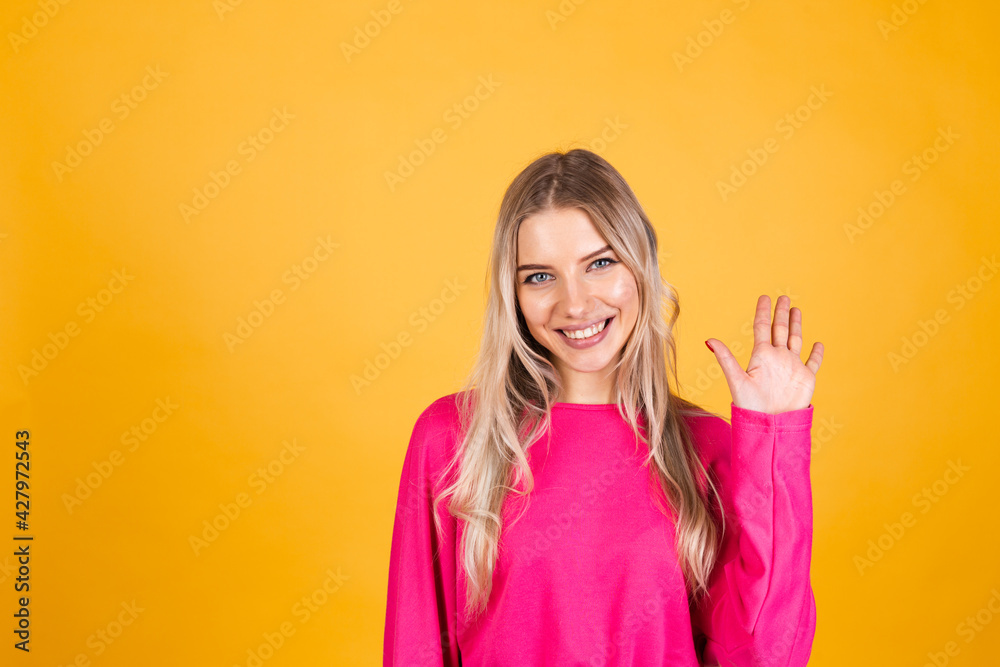 Pretty european woman in pink blouse on yellow background saying hello happy and smiling, friendly welcome gesture Pretty european woman in pink blouse on yellow background saying hello happy and smiling, friendly welcome gesture