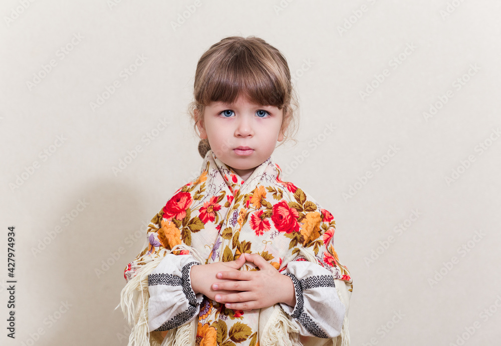 Portrait of small pretty girl in traditional ukrainian style.Young beautiful girl in a long white national shirt and traditional scarf. Ukrainian culture, ethno style. Funny face.. Portrait of small pretty girl in traditional ukrainian style.Young beautiful girl in a long white national shirt and traditional scarf. Ukrainian culture, ethno style. Funny face..
