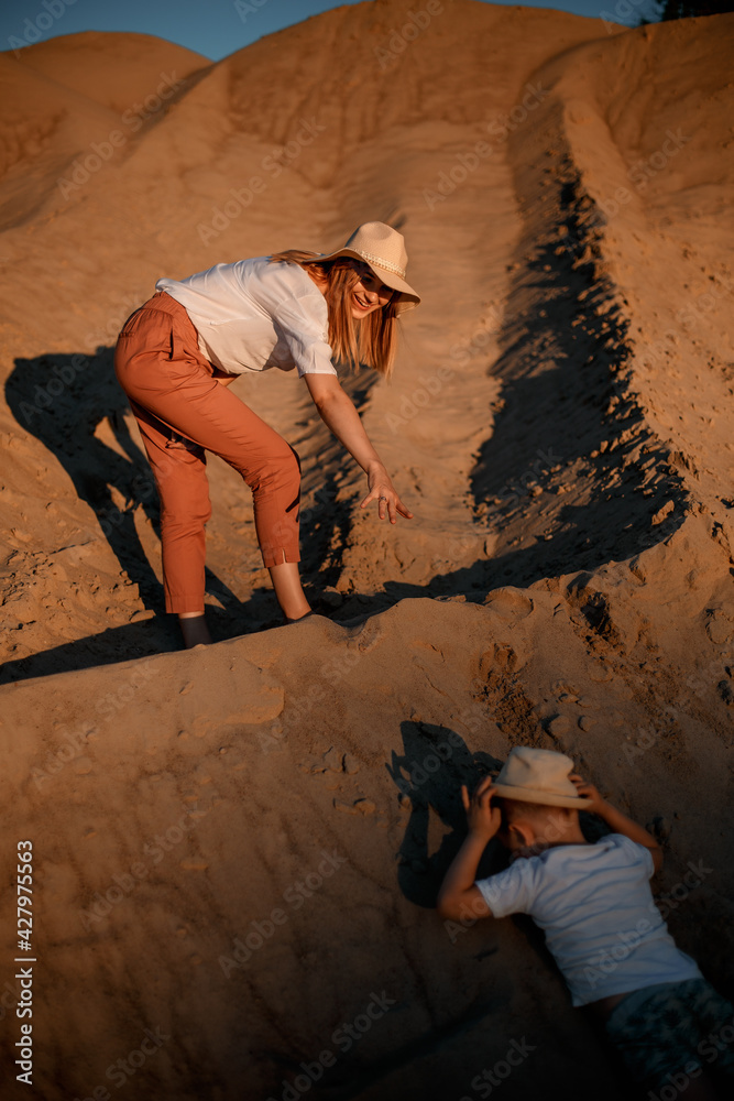 Woman being kissed by her loving son during sunset. Mother with her son on sand dune. Woman being kissed by her loving son during sunset. Mother with her son on sand dune.