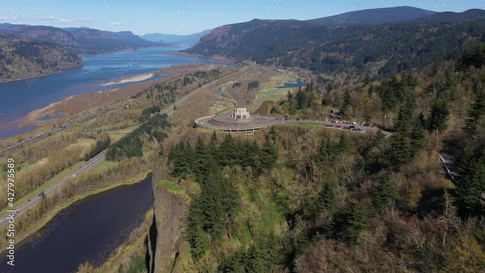 Cinematic bird's-eye drone footage of the famous, popular tourist destination, the Vista House, a scenic overlook with a tower near majestic waterfalls at the Columbia River Gorge near Portland Oregon