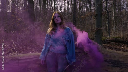 Girl leaning on a Tree out of which comes purple Smoke - Slowmotion photo